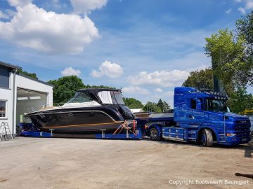 Motoryacht auf dem Tiefladerauflieger auf dem Werftgelände der Bootswerft Baumgart vor der Lackierhalle