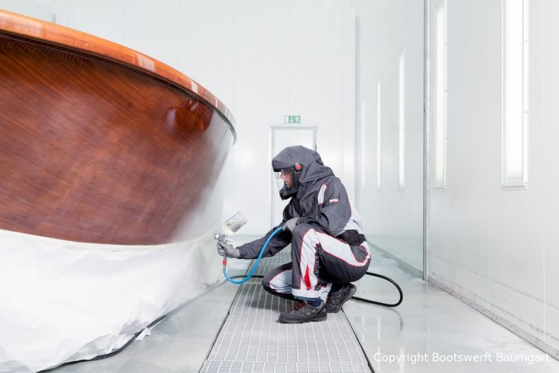 Stefan Baumgart in Schutzkleidung bei Holzlackierarbeiten in der Lackierkabine der Bootswerft Baumgart in Dortmund